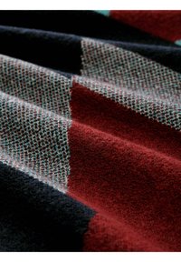 Wollen deken met een geruit patroon in donkerblauw, rood en teal, met een gestructureerde weving en een zachte, pluche oppervlakte.