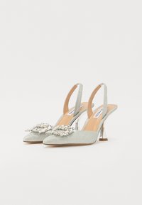 Glitrende sølv slingback hæle med spidse tæer, pyntet med klare sten og et spejlet hældesign.
