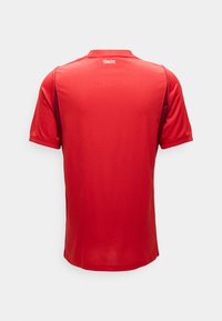 Κόκκινη αθλητική φανέλα με κοντά μανίκια και το κείμενο "TÜRKİYE" στο πάνω μέρος της πλάτης, με σκουρότερα πλαϊνά πάνελ και ριμπ γιακά σε μονόχρωμο φόντο.