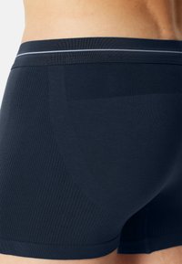Námořnické modré boxerky vyrobené z elastického materiálu s žebrovanou texturou a úzkým elastickým pasem, který má reflexní pruh.