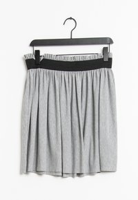 Hame grisifera rayada con una cintura elástica negra, que presenta pliegues y un diseño fruncido. Cuélga de un gancho de plástico negro.