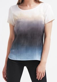 Blusa de manga corta con un diseño degradado, que transita de crema a azul, hecha de una tela suave. Presenta un escote redondo y un corte holgado.