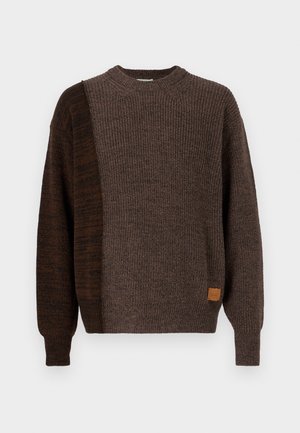 Bruine gebreide trui met een textuurdesign en een puffy silhouet. Inclusief een klein leren label aan de zijkant.