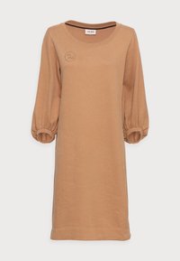 Långärmad klänning i kamelfärg av mjukt tyg. Har en rundad halsringning och samlade manschetter, med en subtil logotyp på bröstet.