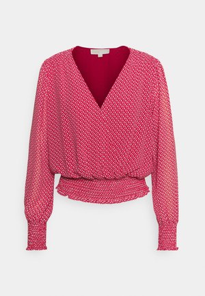 Blouse rouge à manches longues avec petit motif floral blanc, col en V, taille froncée et poignets et ourlet smockés.