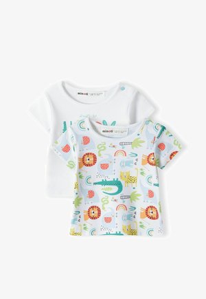 Camiseta blanca de algodón con texto verde, combinada con una camisa de patrón azul claro que presenta animales, frutas y arcoíris en colores brillantes.