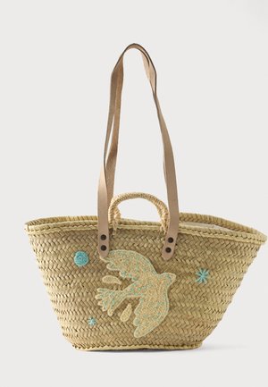 Sac cabas en paille tissée avec des bandoulières en cuir beige, décoré d'un grand oiseau cousu et d'accents brodés bleus.