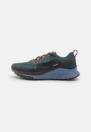 Chaussure de trail Nike vert foncé et marron avec semelle bleue, tige en mesh respirant et languette au talon, vue de profil.