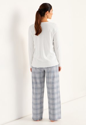 Vit ribbad långärmad topp i kombination med löst sittande pyjamasbyxor i blå och vita rutor, med fransad nederkant och sidfickor.