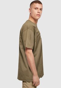 Olijfgroene katoen t-shirt met korte mouwen, relaxed fit, ribbelstructuur, zijnaaddetails en een logo op de voorkant.