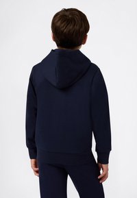 Felpa a girocollo blu navy con tasca a marsupio, polsini e orlo a coste. Realizzata in materiale morbido, presenta un cappuccio sul retro.