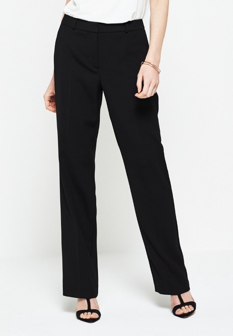 Zwarte, wijde broek van gladde stof met een getailleerde pasvorm. Kenmerkt zich door een middelhoge taille en net geplooide voorkant.