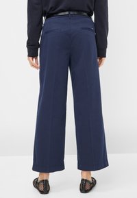 Marineblauwe wijde broek van een zachte, lichtgewicht stof. Voorzien van achterzakken en subtiele naden; gecombineerd met zwarte mesh instappers.