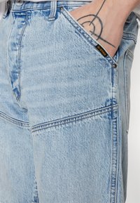 Lichtblauwe denim jeans met een ontspannen pasvorm, zichtbare stiksels en een G-Star label op de voorzak. Voorzien van schuine zakken en een knoopsluiting.