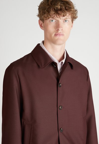 Abrigo burdeos con un corte entallado, que presenta un cuello puntiagudo, cierre de botones en la parte delantera y dos bolsillos laterales; confeccionado con una tela lisa y texturizada.