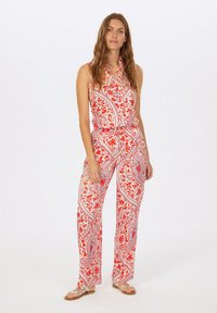 Ärmelloser Overall im rot-weißen Paisleymuster, mit Kragen, tailliertem Bund und weitem Bein. Der Stoff weist aufwendige florale Details auf.