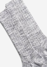 Chaussettes en tricot gris affichant un motif moucheté avec une finition texturée. Le tissu est doux, d'épaisseur moyenne et possède des poignets côtelés.