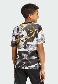 Kortærmet, sort og hvid grafisk T-shirt med dristige gule detaljer, dynamiske tegneseriestil-illustrationer og en behagelig pasform.