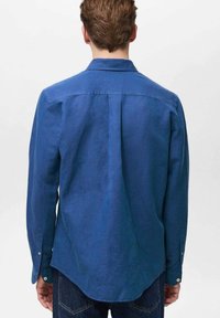 Blauwe lange mouwen shirt van lichtgewicht stof met een rechte pasvorm, puntige kraag en knoopmanchetten. Plisseedetail aan de achterkant.