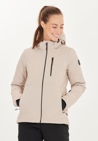 Veste imperméable beige avec une fermeture éclair à l'avant, une capuche, une poche poitrine zippée et des accents noirs. Elle se distingue par une texture lisse et une coupe décontractée.