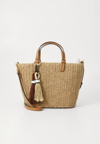 Woven straw handbag with tan leather handles, detachable shoulder strap, and two large fabric tassels in brown and cream colors.