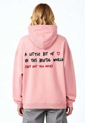 Felpa con cappuccio rosa dal taglio oversize; presenta testo nero e rosso sulla schiena. Il testo recita: "Un po' d'amore in questo mondo brutale."