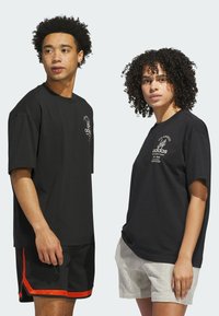 Zwarte katoenen t-shirts met korte mouwen en ronde hals, met daarop witte bedrukte tekst en grafische afbeeldingen. De modellen van de shorts verschillen in ontwerp en kleur.