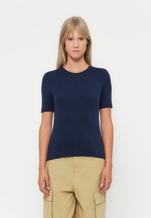 Mørkeblå kortermet t-skjorte laget av mykt stoff; har rund hals og en tettsittende silhuett, kombinert med lyse beige cargo-bukser.