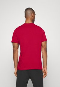 T-shirt di cotone rosso con colletto rotondo e maniche corte. Il retro mostra una trama liscia e un orlo dritto.