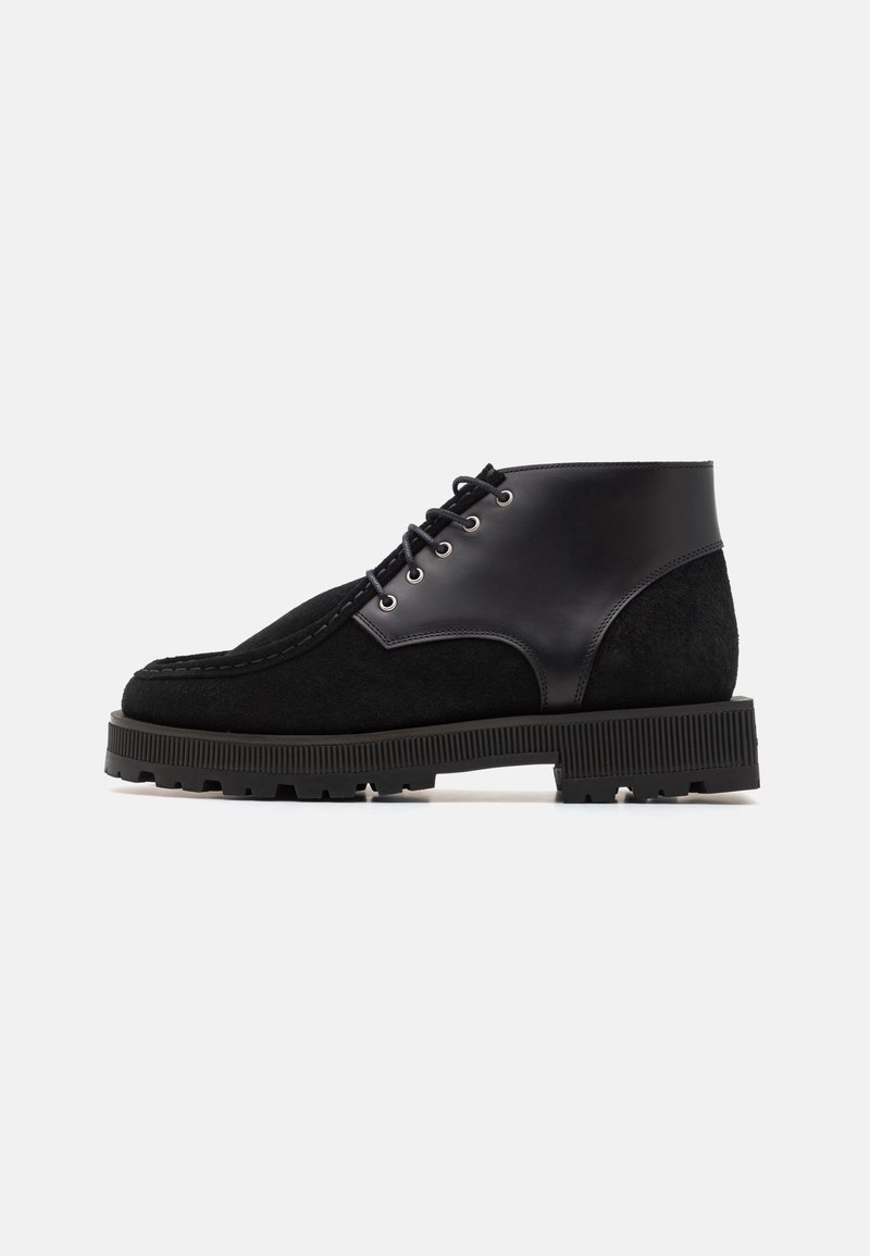 Bottes noires cheville en cuir lisse et daim, bout rond, lacets et semelle en caoutchouc texturée.
