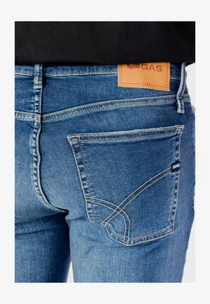 Jeans in denim blu con una patch in pelle del marchio, tasche posteriori con cuciture decorative e un design slim-fit.