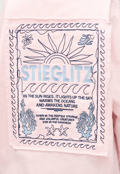 Μπαλώματα σε ροζ ύφασμα με μπλε κεντημένο ήλιο, κύματα, κοράλλια, αστερίες και κείμενο για την ανατολή του ηλίου και τα πλάσματα του βαθιού ωκεανού.