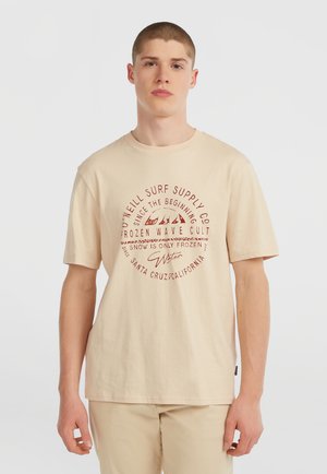 Beige bomulds t-shirt med et cirkulært rødt grafisk print med tekst og bølgedesigns. Korte ærmer og rund hals.