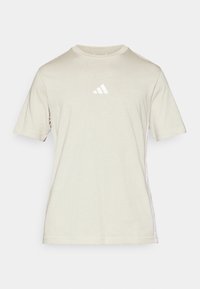 Světle béžové tričko s krátkým rukávem vyrobené z měkké tkaniny má na hrudi malé bílé logo Adidas a bílé postranní akcenty.