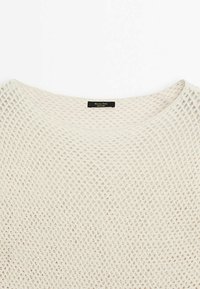 Let, cremefarvet strikket sweater med åbent mesh-design og bred halsudskæring. Mærke syet i sort på indersiden af kraven.