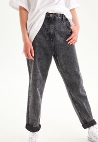 Jeans negri din denim, cu talie înaltă, cu o textură ușor decolorată, croială dreaptă, manșete răsucite și închidere cu nasture frontal.