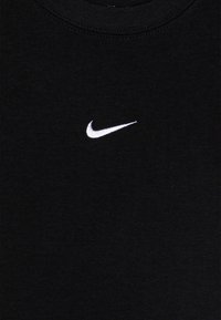 T-shirt en coton noir présentant un logo Nike swoosh blanc brodé sur la poitrine gauche. Design à col rond avec une texture douce.