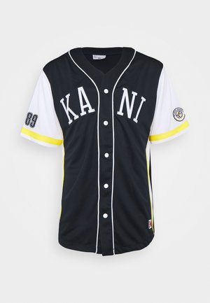 Czarna i biała koszulka baseballowa zapinana na guziki z napisem „KANI”, żółte paski na rękawach, numer 89 na lewym rękawie i okrągłe logo na prawym rękawie.