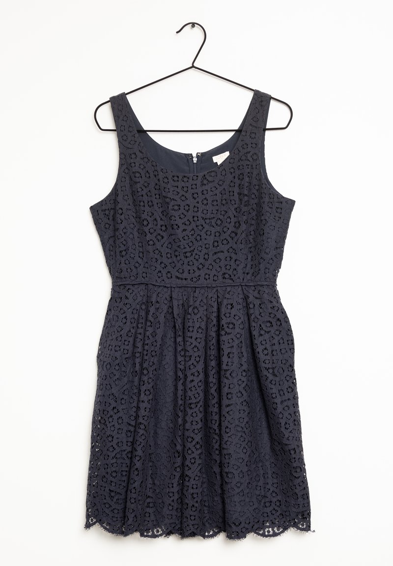 Robe noir sans manches en dentelle avec encolure ronde et taille cintrée, suspendue sur un cintre noir sur fond blanc.