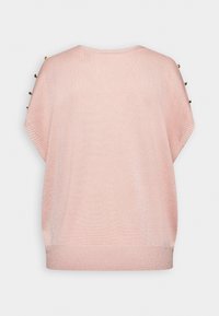 Un pull oversize rose clair avec une texture lisse, présentant des accents de boutons dorés aux épaules et un col rond.