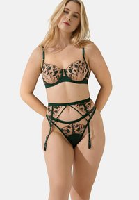 Ensemble de lingerie vert en dentelle comportant un mesh transparent avec broderies florales, un soutien-gorge à armatures avec bretelles réglables et une ceinture porte-jarretelles avec des straps.