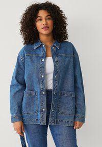 Denimjack in medium blauw met een relaxte fit, knoopsluiting, twee voorzakken en een klassieke kraag. Gestructureerde stof met zichtbare stiksels.