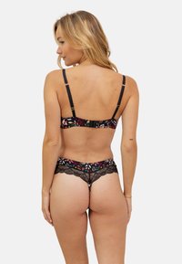 Ensemble de lingerie en dentelle florale noire comprenant un soutien-gorge à motif avec des bretelles réglables et un string assorti avec des détails en dentelle et un design floral coloré.
