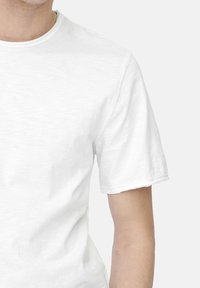Weißes T-Shirt mit kurzen Ärmeln aus weicher Baumwolle, mit einfachem Rundhalsausschnitt und leicht erkennbarer Textur auf dem Stoff.