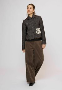 Černá texturovaná bunda s krajkovou kapsou, knoflíkovým zapínáním a límcem, doplněná hnědými širokými manžetovými manžetami.