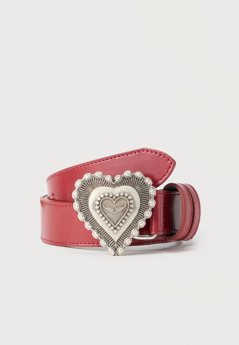 Κόκκινη δερμάτινη ζώνη με διακοσμητική ασημένια πόρπη σε σχήμα καρδιάς, διακοσμημένη με ανάγλυφα κυκλικά μοτίβα και ένα μικρό φτερωτό έμβλημα στο κέντρο.