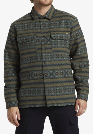 Knap-up skjorte i grøn, med geometriske mønstre i brun og gul. To brystlommer, lange ærmer og en krave-neckline.