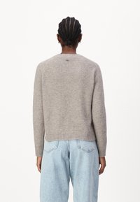 Grijze wollen trui met een geribde onderrand, ronde halslijn en raglanmouwen, gecombineerd met lichtblauwe hoge taille jeans.