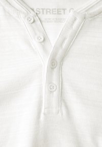 Camisa henley de rayas blancas con tapeta de botones, que presenta tres botones blancos y una tela texturada.