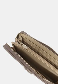 Portafoglio marrone testurizzato con chiusura a zip, che presenta svariati scomparti interni e una fodera beige liscia.